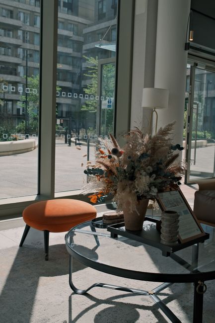 A large floral arrangement featuring a variety of fresh flowers and dried botanical elements, including pampas grass, dried eucalyptus, and muted-toned blooms in shades of beige, white, and dusty pink